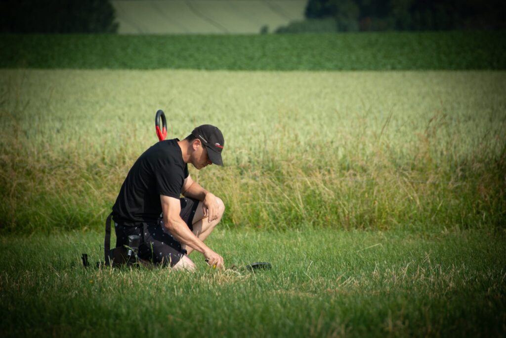 Een jonge metaaldetectorist bekijkt een vondst in het gras