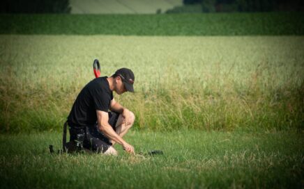 Een jonge metaaldetectorist bekijkt een vondst in het gras