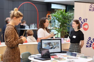 Drie vrouwen bij een stand op de Dag van het West-Vlaamse Onderzoek