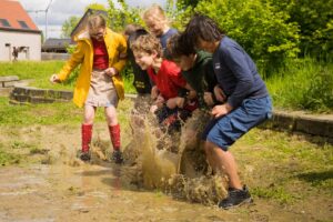 Kinderen van de jeugdbeweging spelen in een plas modder