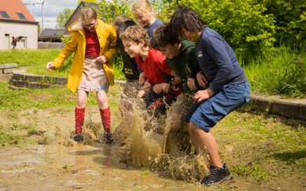 Kinderen van de jeugdbeweging spelen in een plas modder