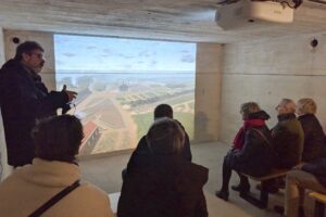 Een gids projecteert een virtuele omgeving op een muur in een bunker