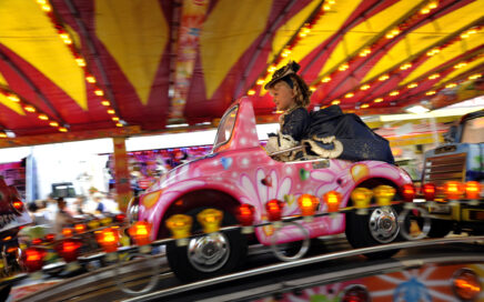 Meisje zit in een kleurrijke draaimolen op de kermis.