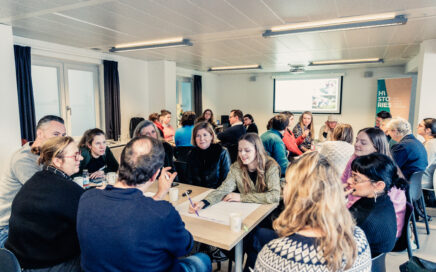 Een groep mensen zit aan tafel. Ze brainstormen op een groot wit blad. Histories medewerker Morgane is aan het schrijven.