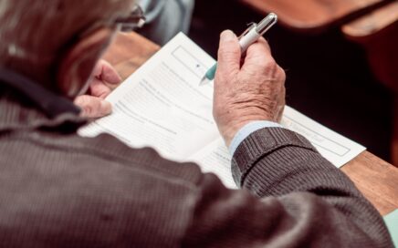 Een man kijkt in een programmaboekje. Hij heeft een pen in de hand.