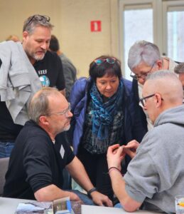 Archeoloog Ricca Annaert en een groep metaaldetectoristen nemen een vondst onder de loep tijdens de studiedag metaaldetectie en de Merovingische periode van Histories.