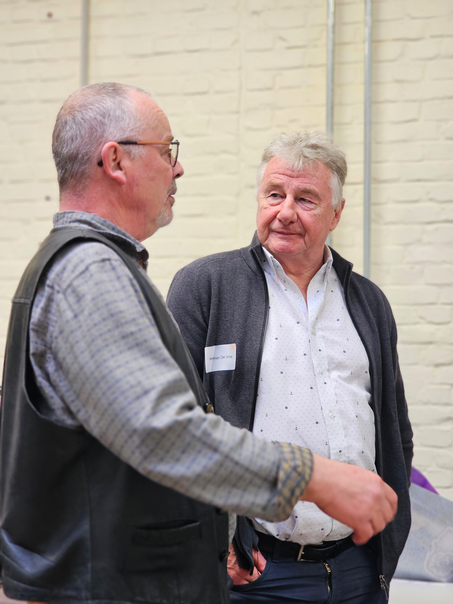 Twee oudere mannen in gesprek tijdens de studiedag metaaldetectie en de Merovingische periode van Histories. Ze dragen beiden een hemdje.
