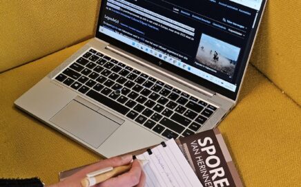 De Wikipediapagina van de Paardenprocessie Hakendover staat open op een laptop. Ernaast ligt een notitieboek. Je ziet een hand schrijven.