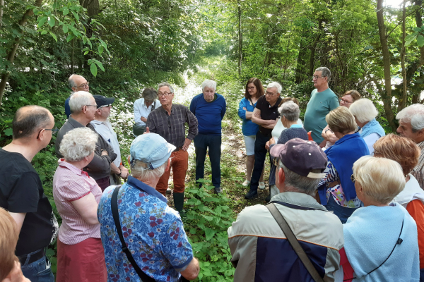 Een groep staat rond een gids in het bos. Ze luisteren geboeid