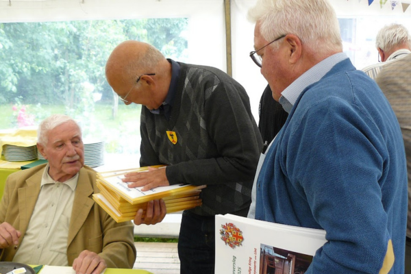 Drie oude mannen. Twee mannen schenken een boek cadeau aan de derde man.