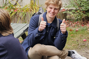 Blonde jongeman steekt zijn twee duimen op