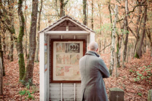 Man staat in het bos voor een grenspaal