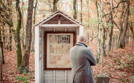 Man staat in het bos voor een grenspaal