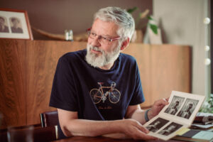 Portret van Peter Eyckerman die oude familiefoto's toont