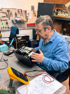 Man in jeanshemd herstelt een oude radio 