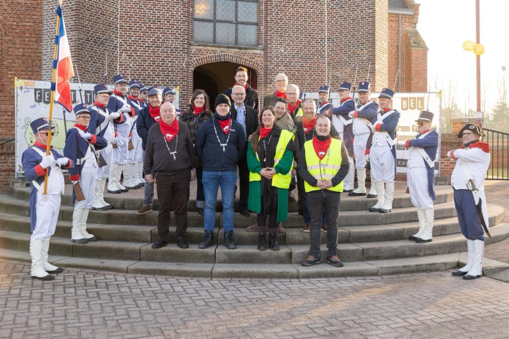 Groep mensen op de trappen van een kerk die geflankeerd worden door muzikanten in uniform