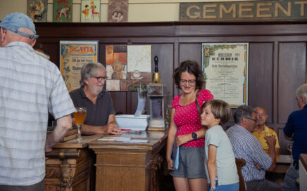 Moeder en zoon staan aan de bar die wordt bediend door een man met bril en baard